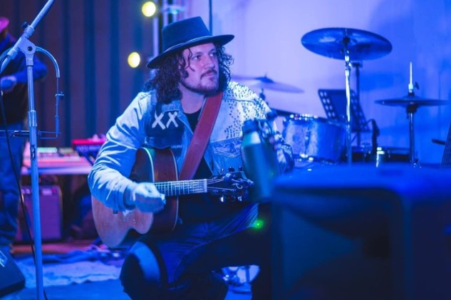 Photo of Tyler Gould holding a guitar on stage.